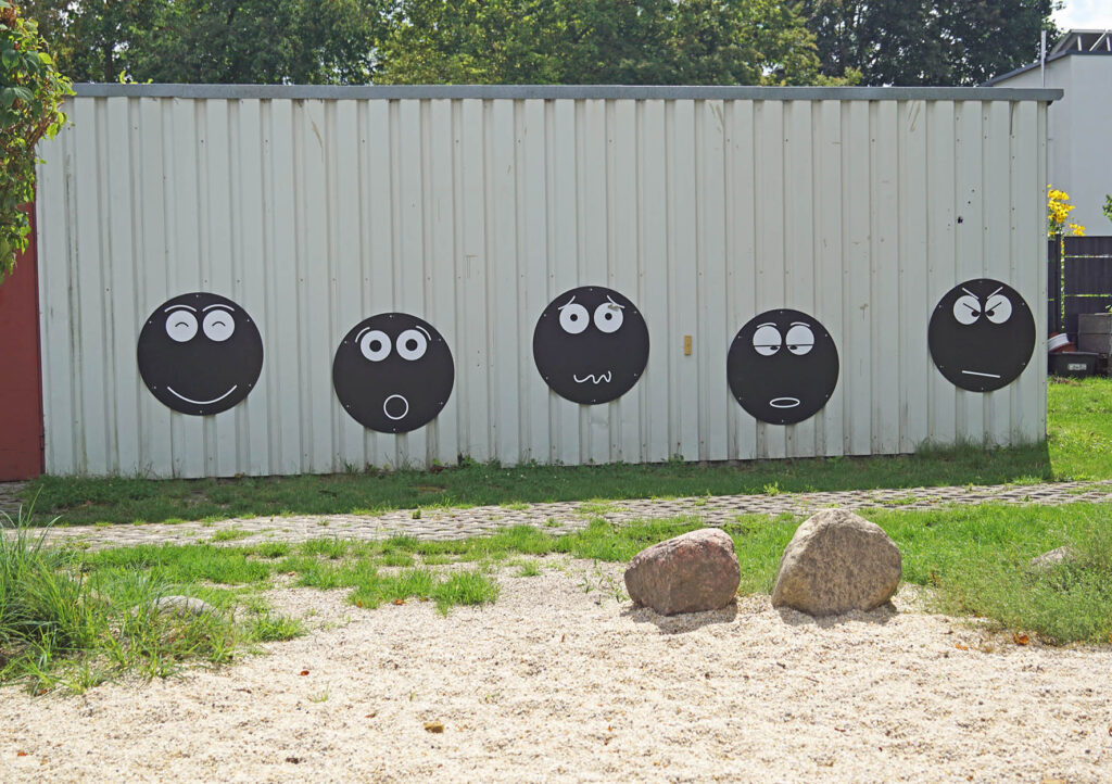Kreidesmileys an einer Wand am Spielplatz