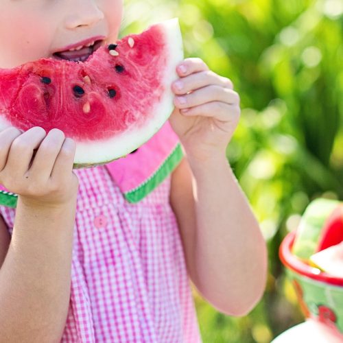 Ein Mädchen isst ein Stück Melone